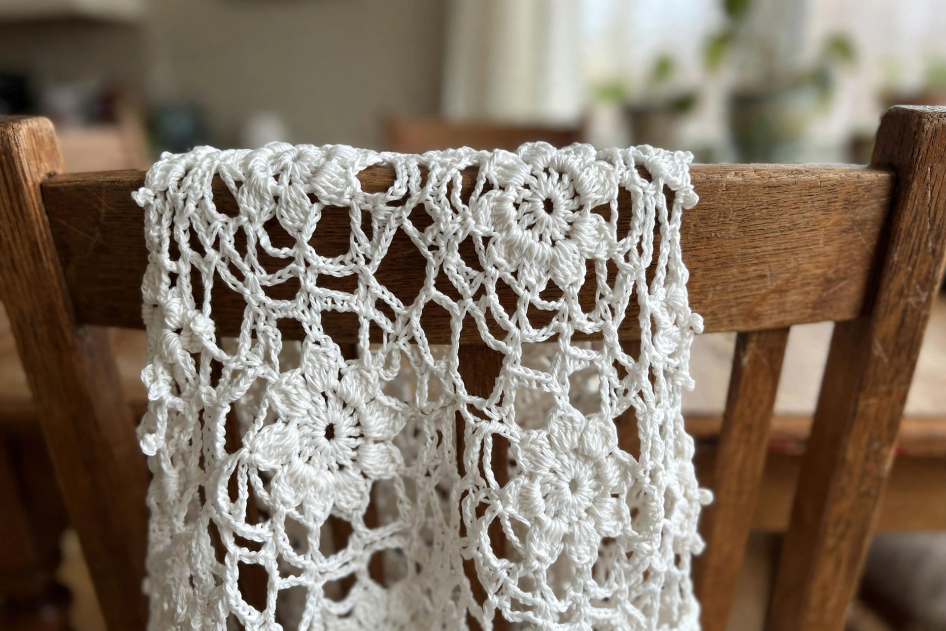 Close-up of the white floral lace motifs on the crochet shawl draped over a chair
