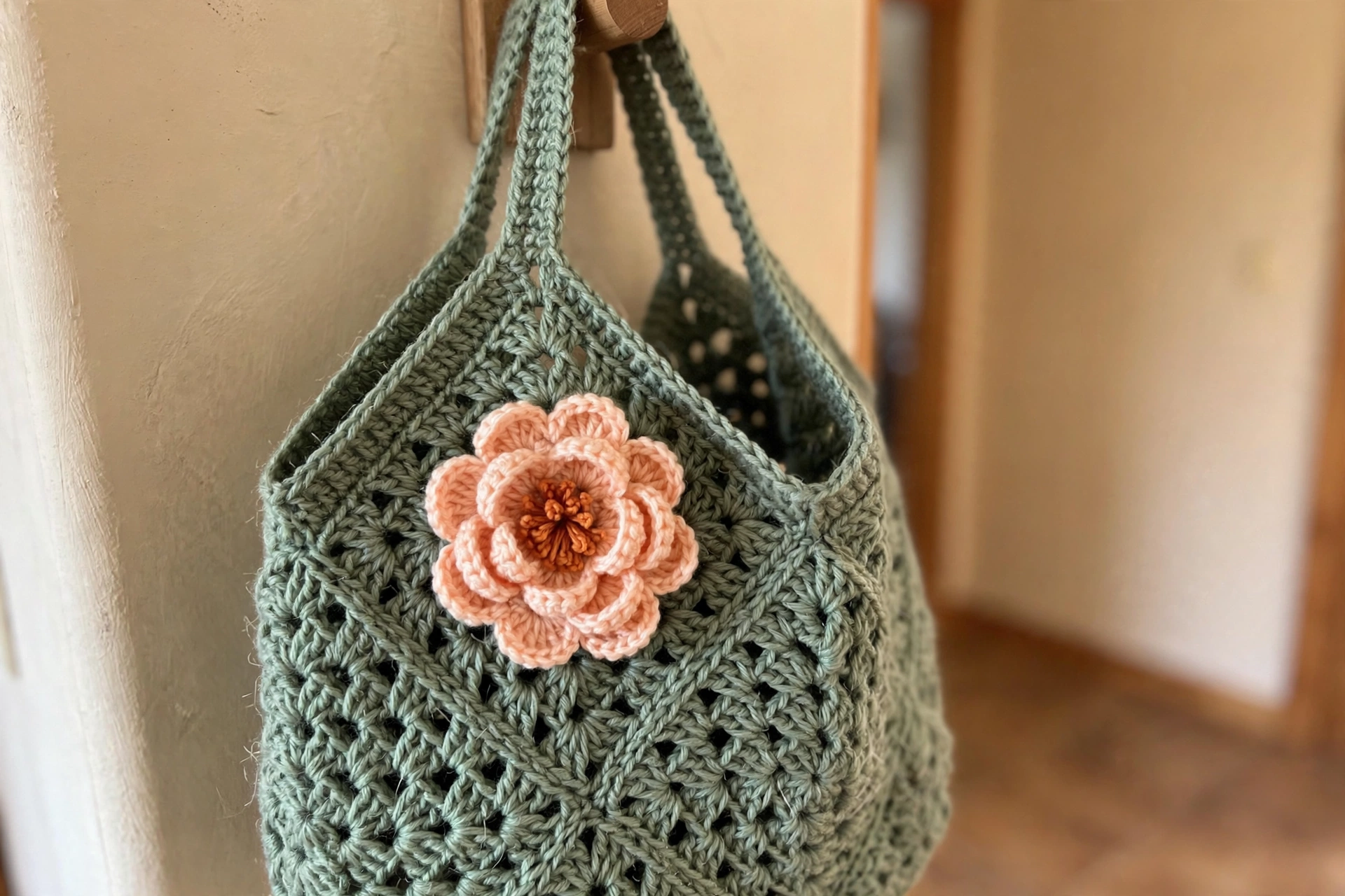 Close-up of a peach peony flower sewn on a sage green granny square of the tote bag