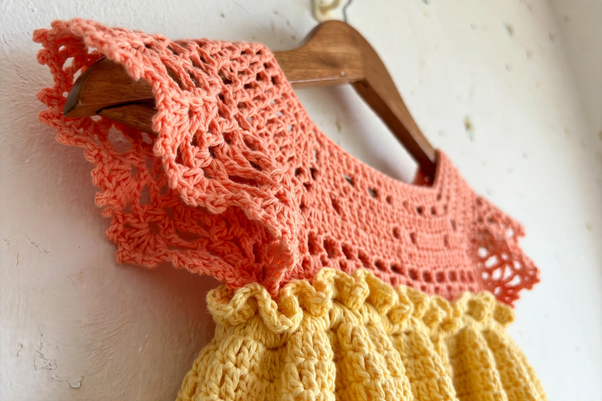 Close-up of the lacy coral flutter sleeve and gathered butter-yellow waist of the dress