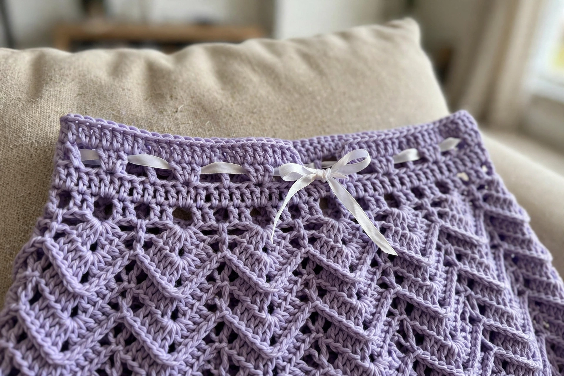Close-up of the crocheted eyelet row with white satin ribbon threaded through on the Lavender Cottage Babydoll Dress