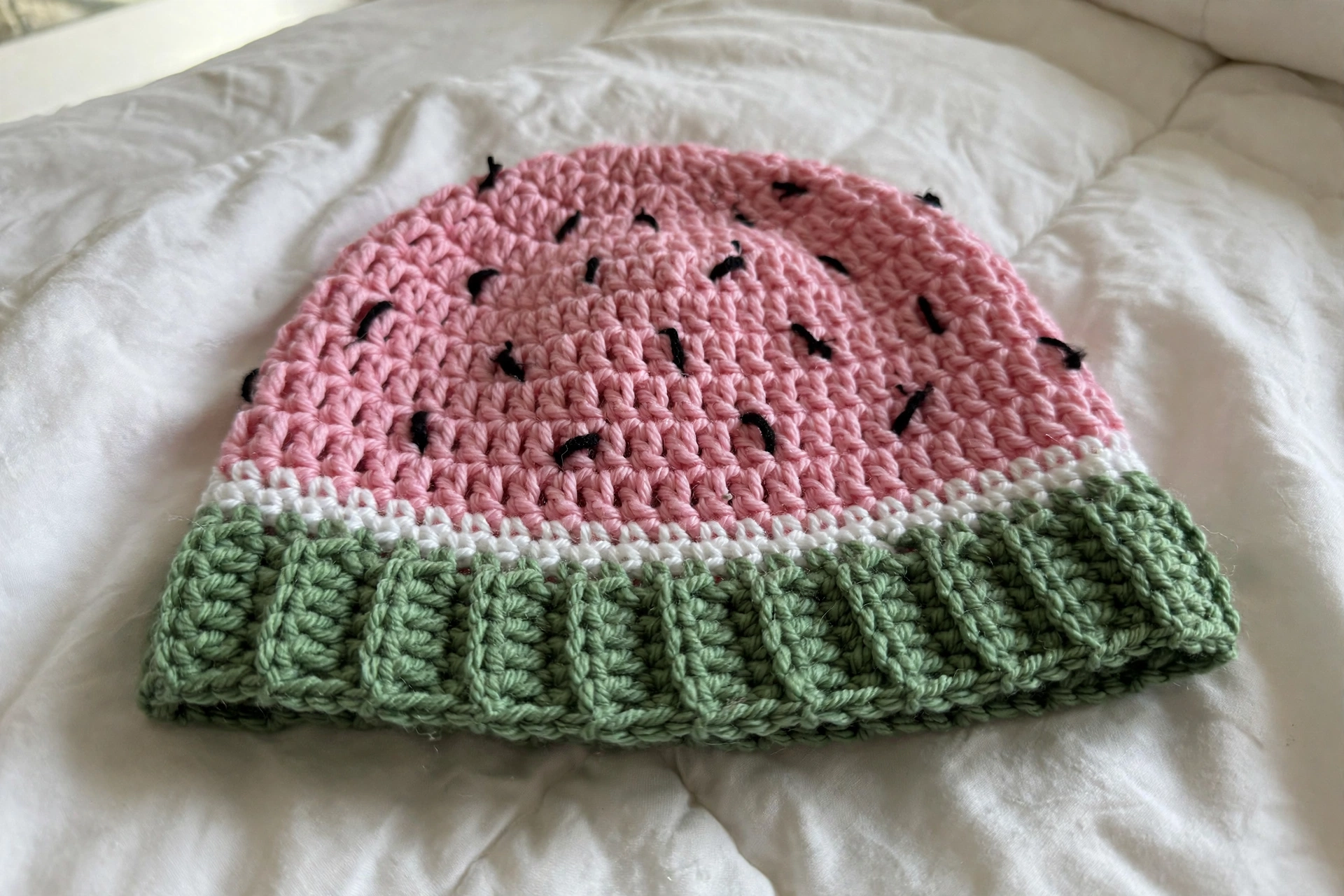 Close-up of the watermelon hat with embroidered seeds, white rind stripe, and green ribbed brim