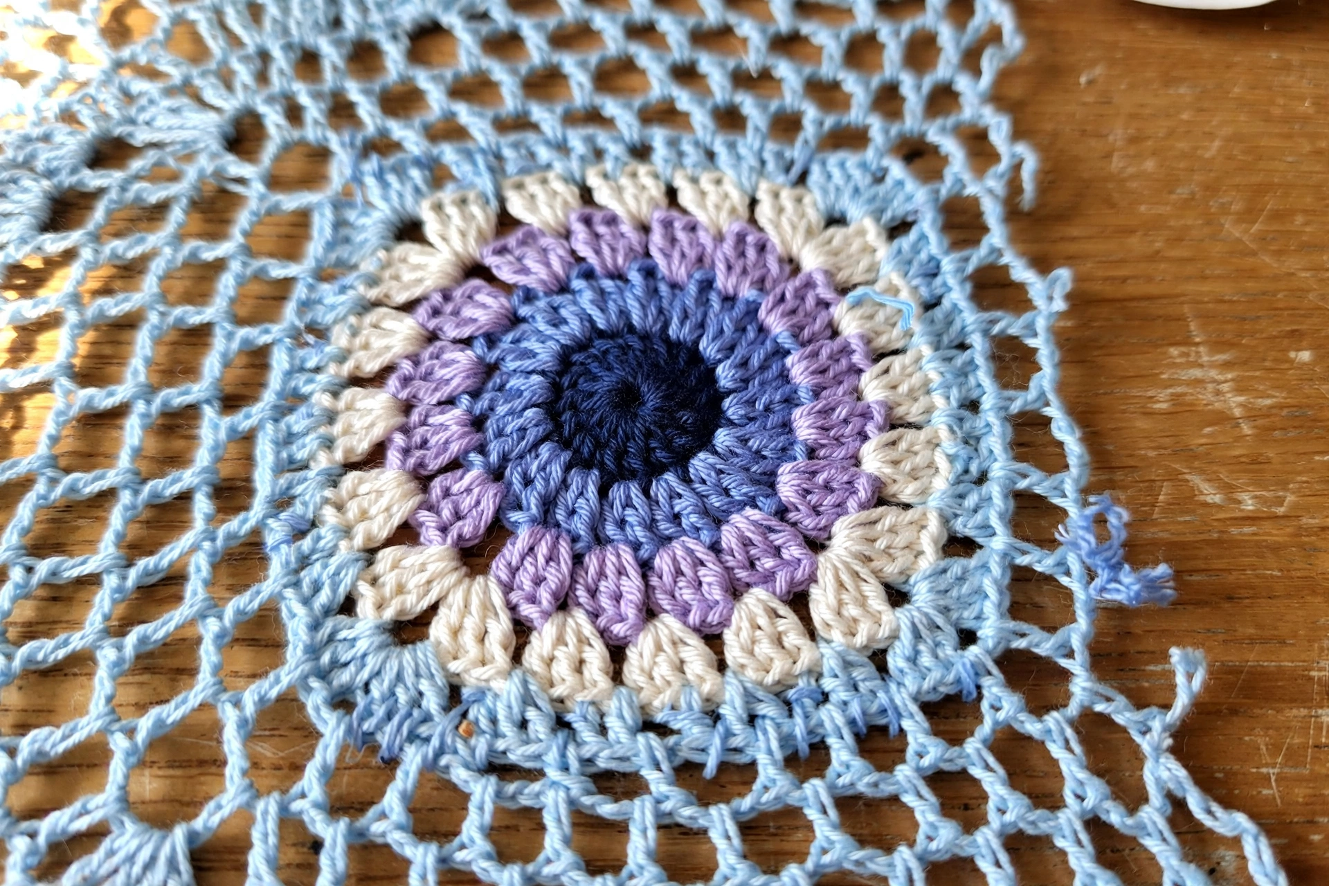 Close-up of the bluebell granny square applique on the shell mesh romper fabric