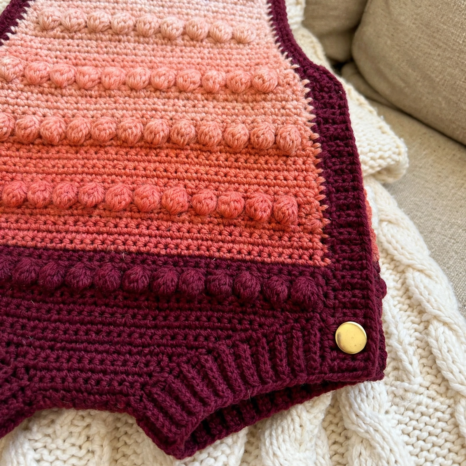 Close-up of the sunset gradient bobble stitch texture and gold snap on the baby romper