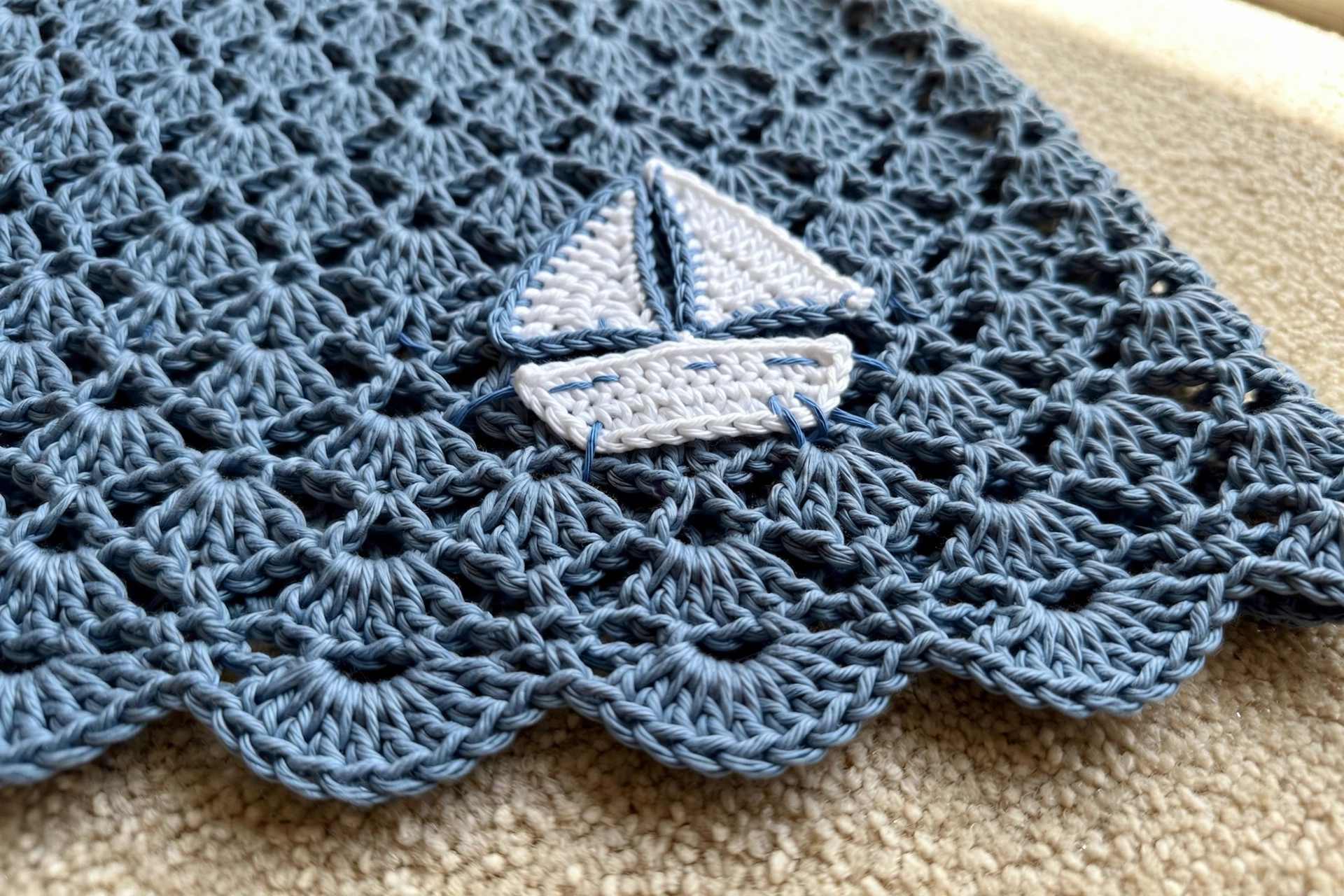 Close-up of the dusty blue lace shell skirt with a white crochet sailboat applique