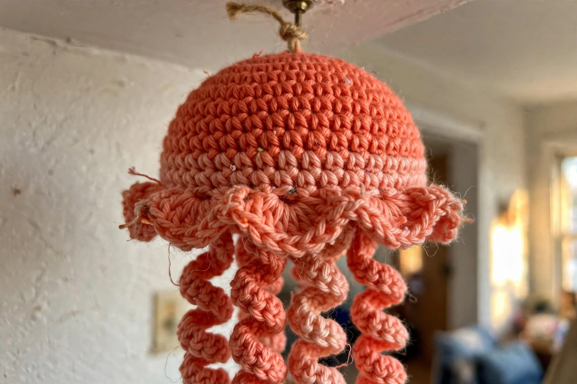 Close-up of a coral ombre crochet jellyfish bell with shell ruffle and spiral tentacles