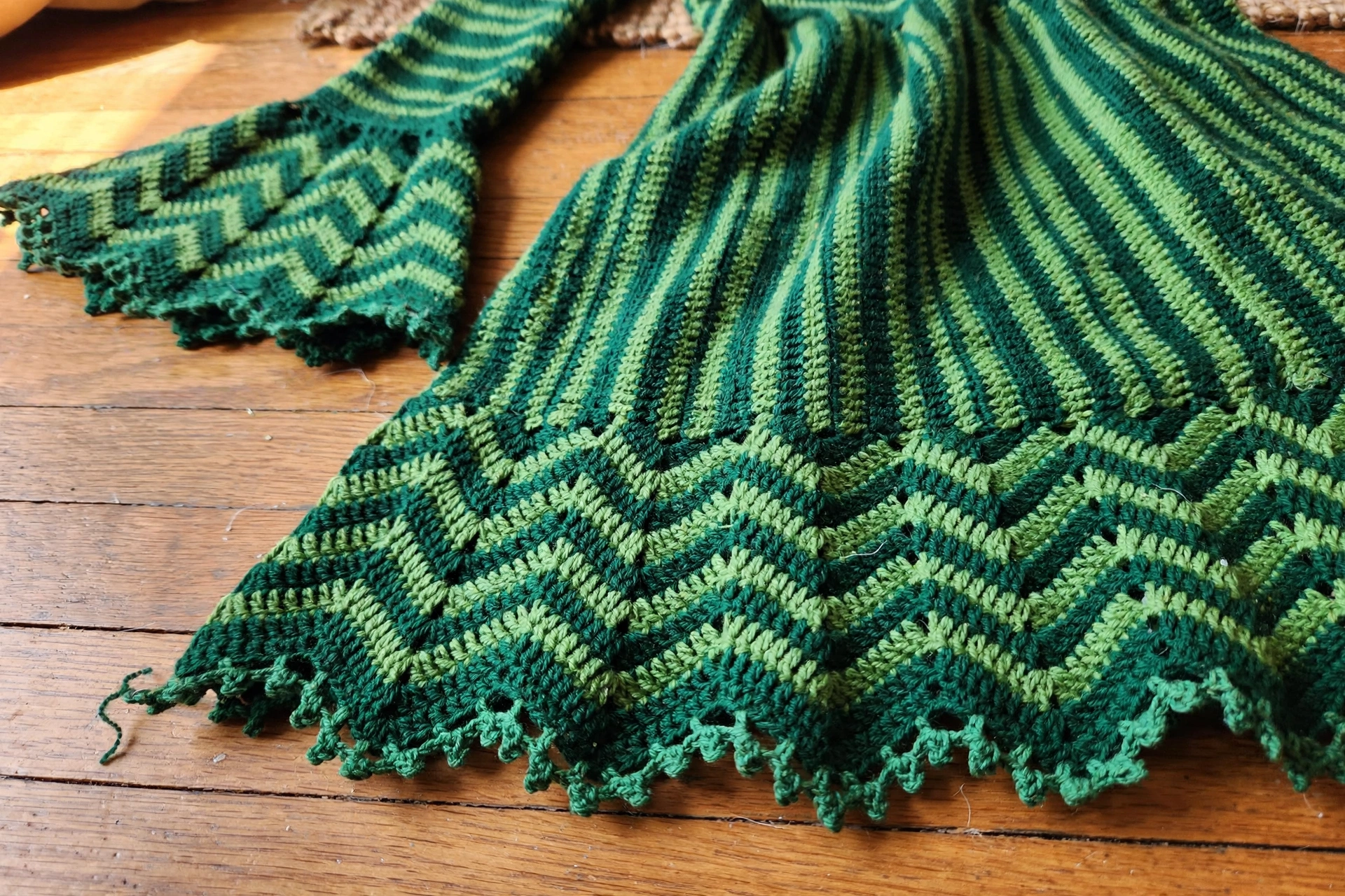 Close-up of the chevron hem, picot scallop edge, and flared bell sleeve cuff on the green crochet dress